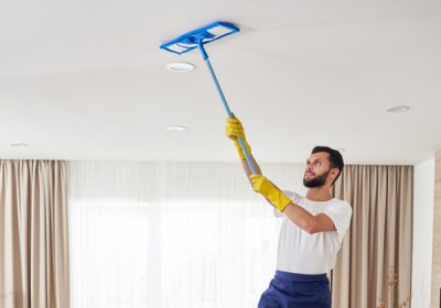 Man,Cleaning,Ceiling,And,Lamps,In,Living,Room.,House,Cleaning